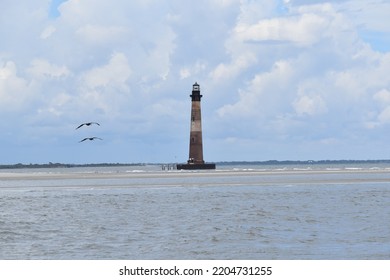 Two Birds Flying Toward A Lighthouse