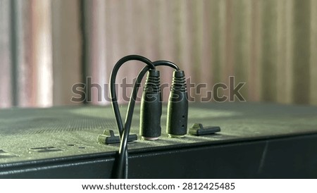 Two black audio jack cables connected to a device in a studio setting