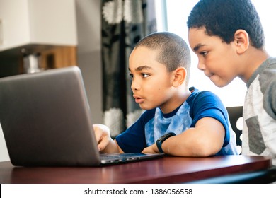 Two Black Boy Sitting Playing On A Laptop Computer At Home