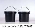 Two black buckets. New plastic buckets without inscription. Concept for production of plastic containers. Buckets on white. Plastic container for storage and transportation of chemical products