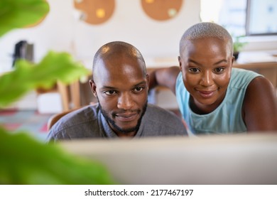 Two Black Coworkers Look At A Computer Screen In A Creative Office