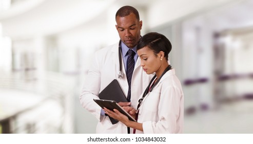 Two Black Doctors Discuss Their Patient While On Their Tablets