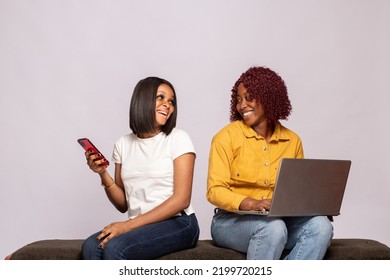 Two Black Girls Sitting Together Using Phone And Laptop