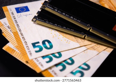 Two black RAM modules placed on multiple euro banknotes, representing the concept of expensive computer memory and high investment in PC hardware components.