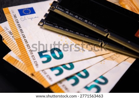 Two black RAM modules placed on multiple euro banknotes, representing the concept of expensive computer memory and high investment in PC hardware components.
