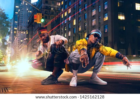 Two black rappers dancing on city street
