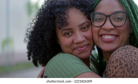 Two black sisters showing love and affection. African American sibling kissing friend in cheek. Happy Hispanic South American people care - Powered by Shutterstock