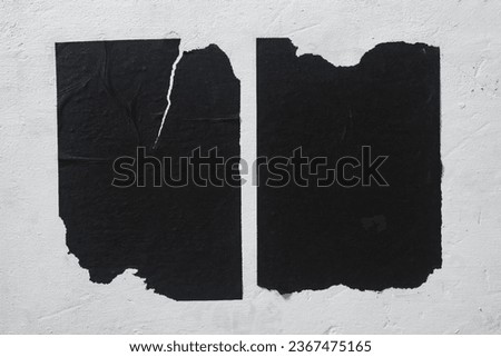 Two black torn sheets of paper on the wall.