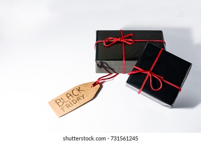 Two black wrapped gift boxes with a red cord and a Black Friday 2017 sales tag handwritten on a cardboard