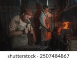 Two blacksmiths work in an old rural forge. Traditional crafts