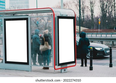 Two blank advertising billboard at the glass bus stop on a street full of people. Crowd. Winter. Cold. Line. Waiting for public transport. Business. Mockup. Cold