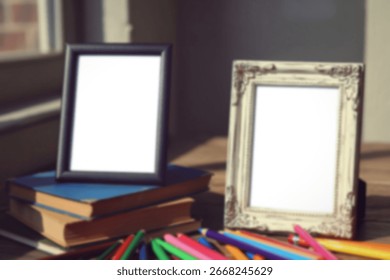 Two blank picture frames, one modern black and one ornate white, rest on a stack of books alongside a scattering of colorful pencils.