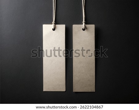 Two blank rectangular beige tags with rounded corners and string attachments, hanging against a dark background – Minimalist Branding Concept
