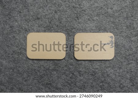 Two blank rectangular wooden plaques on a textured surface