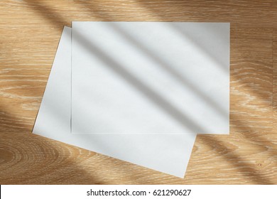 Two Blank Sheets Of Paper On Wooden Background In Sun Rays