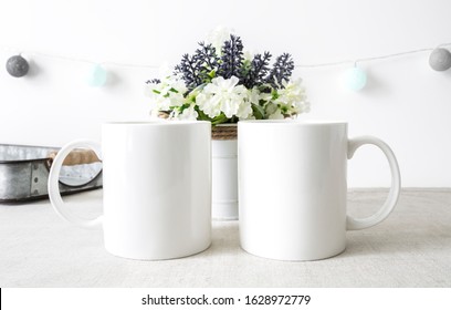 Two blank white 11oz coffee mugs side by side in kitchen setting on white background, friendship mugs mockup - Shutterstock ID 1628972779