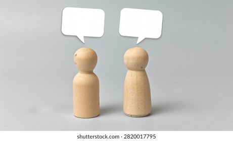 Two Blank White Speech Bubbles Above Wooden Dolls Representing Conversation Communication Dialogue Discussion Feedback and Copy Space Concept. 