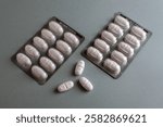 Two blister packs of white tablets with A9 imprint and three loose pills on a gray surface. Medical and pharmaceutical concept