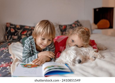 Two blond cute children, boy and girl, siblings and maltese dog, reading book together at home, joy and happiness - Powered by Shutterstock