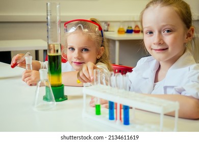 two blonde chemist school kid student little girls (girlfriend sisters) chemical experiment white medical gown classroom science