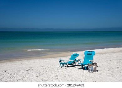 Two Blue Beach Chairs And A Tote Bag On The Beach 