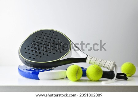 two blue and black paddle rackets on white table with balls and white isolated background. Front view.