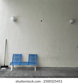 Two blue chairs leaning against a wall with two white spherical lights above them. This minimalist scene reflects simplicity and tranquility. - Powered by Shutterstock