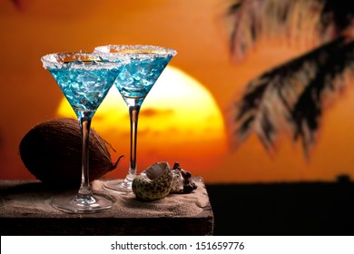 two blue cocktail on beach, sunset, palm tree, coconut