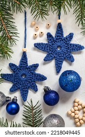 Two Blue Crochet Handmade Christmas Tree Toys And Fir Branches On A White Background. Handmade Knitted Christmas Decor. Homemade Christmas Ornaments.