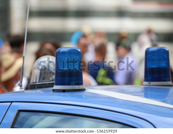 two\
blue lights of an italian police car and many\
people