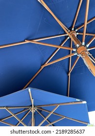 Two Blue parasol umbrellas with wooden linkage in summer
