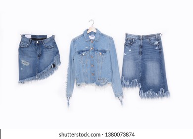 Two Blue torn skirt Jeans and jeans jacket on hanging -white background
