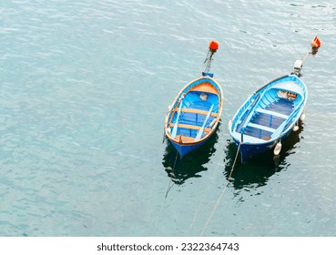 Two blue traditional style wooden fishing dinghies moored in sea