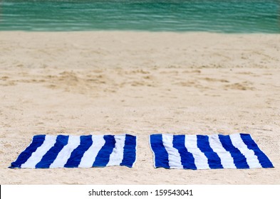 Two Blue And White Stripes Towels On Sandy Beach Against Turquoise Water  In A Tropical Island.  Concept Photo Of Travel , Holiday, Vacation And Tourism.No People. Copy Space.