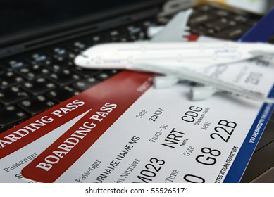 Two boarding passes with a white model airplane on a laptop keyboard. An idea about aviation or ticket reservation nowadays can be done easily online at hand by using web browser and the internet. - Shutterstock ID 555265171