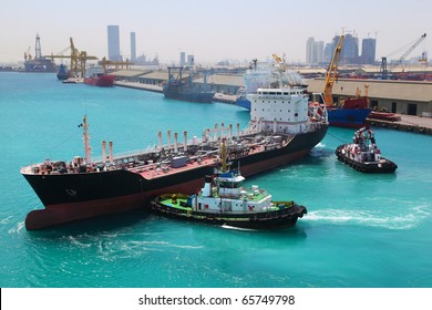 Two boats docked to industrial ship in port sail to sea at sunny day  in Abu Dhabi