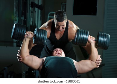 Two bodybuilders training in gym