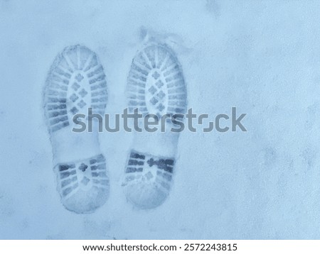 Two boot prints are visible in the snow.
Concept of tracks in snow.