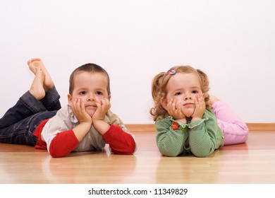 Two Bored Kids Laying On The Floor Propping Their Heads