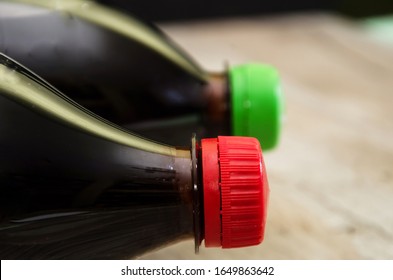 two bottles of carbonated drink on a wooden background. Close-up. Top of bottles with cap.