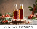 Two bottles of herbal syrup made of fresh wild rowanberry with fresh fruit on a table