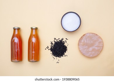 Two Bottles Of Kombucha Tea, Scoby, Brew And Bowl Of Sugar On Yellow Pastel Background. Ingredients For Preparing Healthy Fermented Drink. Flatlay Mockup