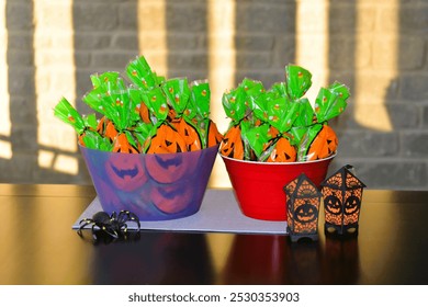 Two bowls filled with pre-packaged bags of candy along with a big black plastic spider and black and orange lanterns wait for trick or treaters on Halloween. - Powered by Shutterstock