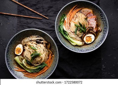 Two bowls of ramen soup with pork, shiitake and enoki mushrooms, marinated egg and vegetables - Shutterstock ID 1722580072
