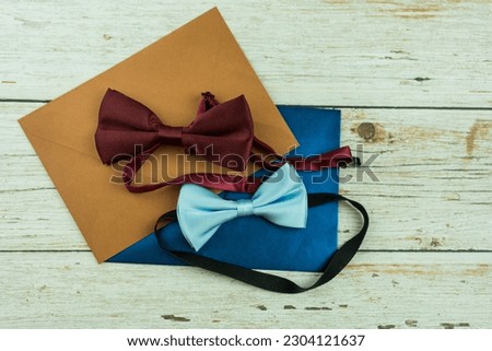 Two of bowtie on a wedding invitation. Wedding set with bowtie and two envelope and an invitation form on a wooden background