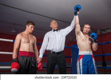 Two Boxer Men Standing In Ring. Referee Lifting Winner Hand Announcing Victory