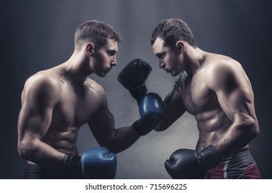Two boxers in boxing gloves met with glances against a dark background