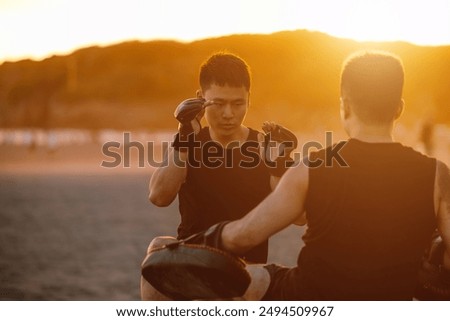 Two boxers are practicing Muay Thai on the beach. Muay Thai practice at dusk and sunset