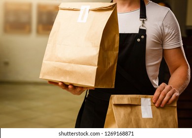 Two boxes with fast food being carried by delivery man in uniform for one of clients - Shutterstock ID 1269168871