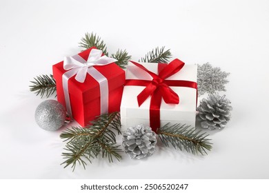 Two boxes with a gift tied with satin ribbons, a fir branch and Christmas tree decorations on a white background. - Powered by Shutterstock